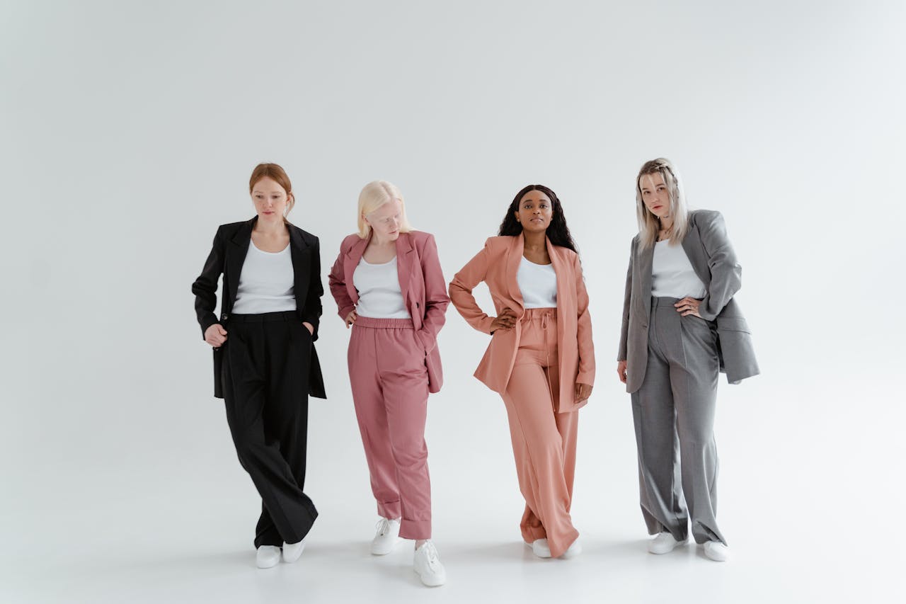 Four women posing confidently in colorful business suits against a white studio background.